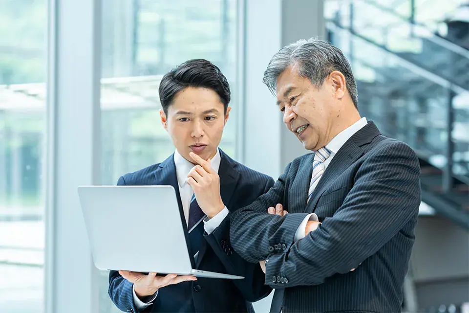 クライアントのデータを確認しながら経営層に提案する代理店のシニアディレクターと若手メンバー